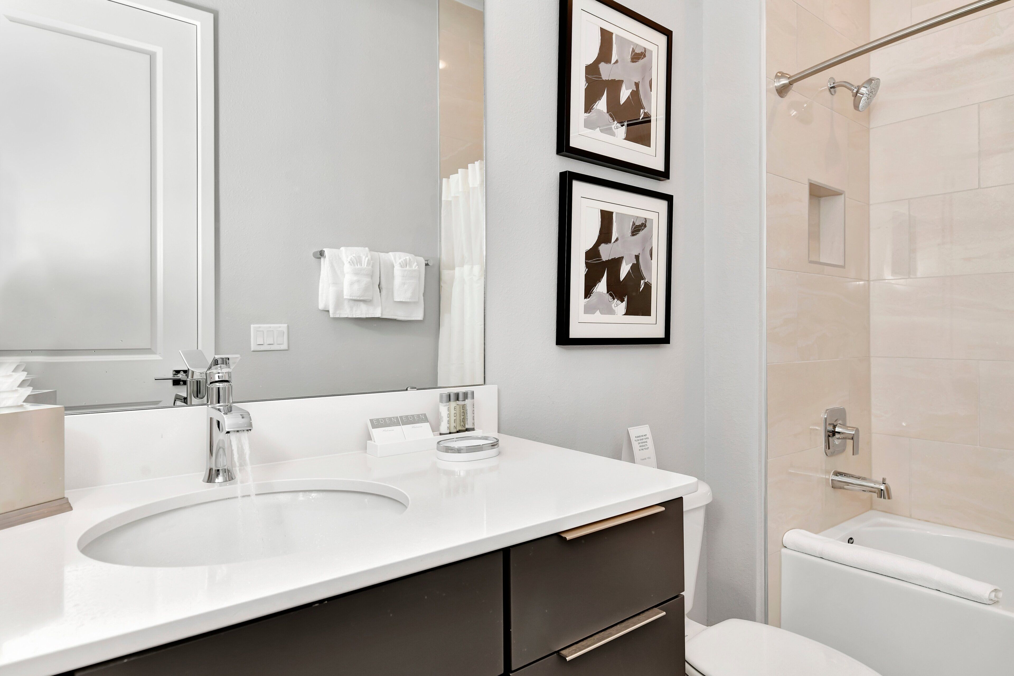 A modern bathroom with a white sink, a mirror, a toilet, and a shower.
