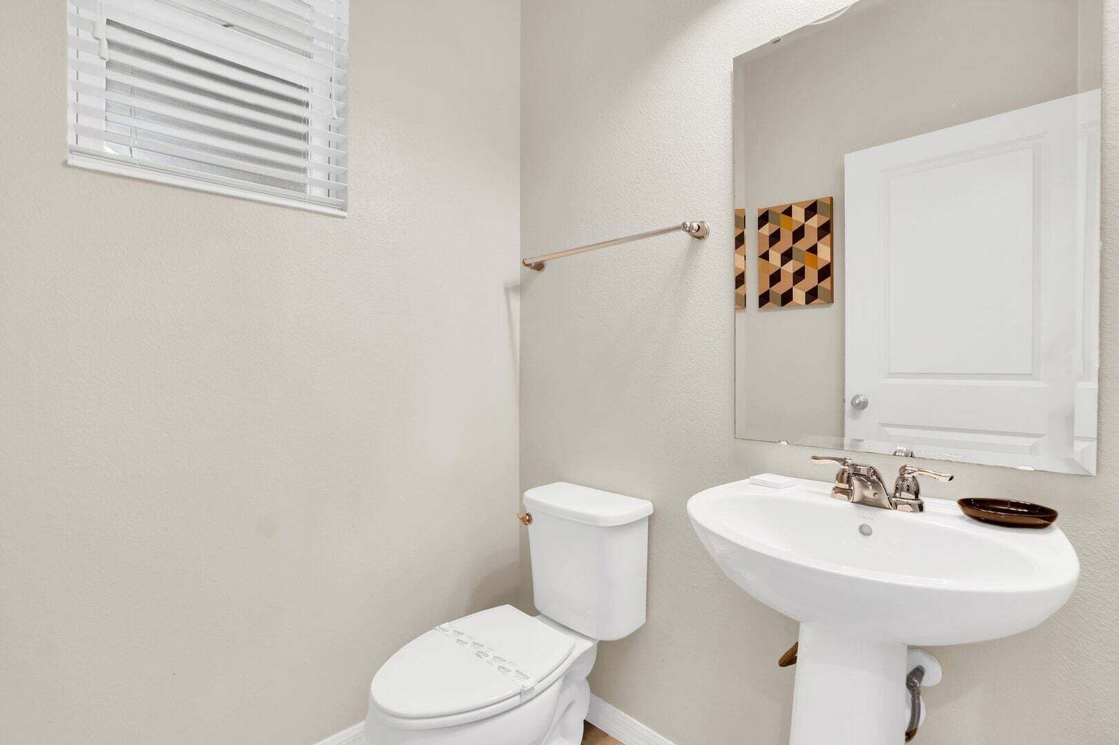 A bathroom with a toilet, sink, and a towel rack.