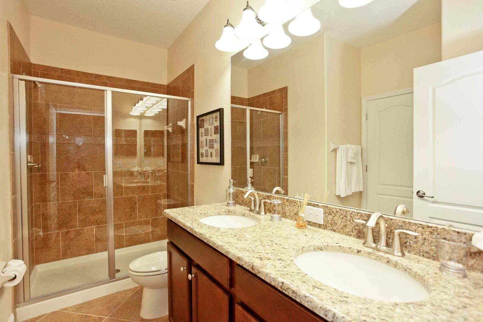 A bathroom with a walk-in shower, two sinks, a large mirror, and a framed picture on the wall.