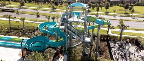 A water park with a large spiral slide and a separate slide area, surrounded by a residential neighborhood.