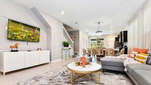 A modern living room with a sofa, a coffee table, and a TV mounted on the wall. - Wonderful House 5 En-suites Free Access to Amazing Resort! (Davenport)