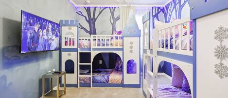 A child's bedroom with bunk beds, a TV, and a tree mural.