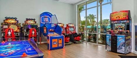 Una stanza con giochi arcade, un tavolo da biliardo e ampie finestre.