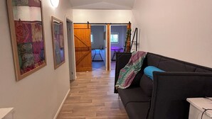 A hallway with a wooden ceiling, a black sofa, and a painting on the wall. - Back to nature rainforest retreat, in the centre of the Sunshine Coast Region. (Rosemount)