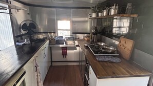 A compact kitchen with a central island, a window providing natural light, and a fan on the left. - Back to nature rainforest retreat, in the centre of the Sunshine Coast Region. (Rosemount)