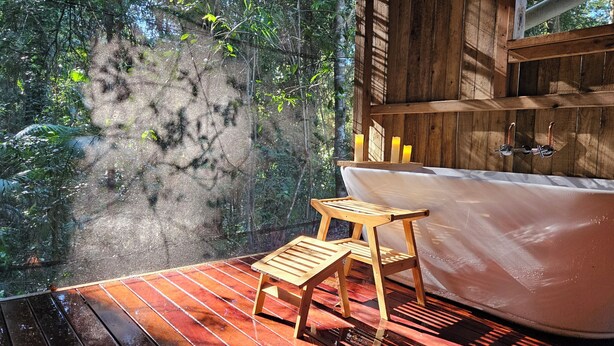 A wooden deck with a bathtub and a small wooden stool. - Back to nature rainforest retreat, in the centre of the Sunshine Coast Region. (Rosemount)