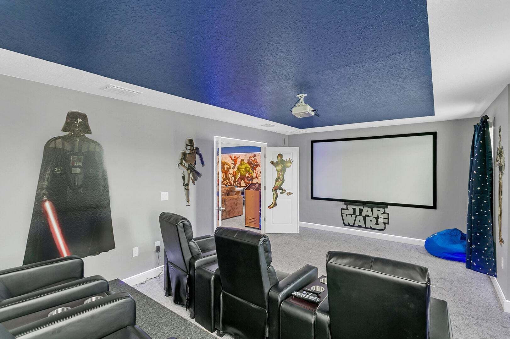 A home theater room with a Star Wars theme, including a projector screen, reclining chairs, and themed decorations.