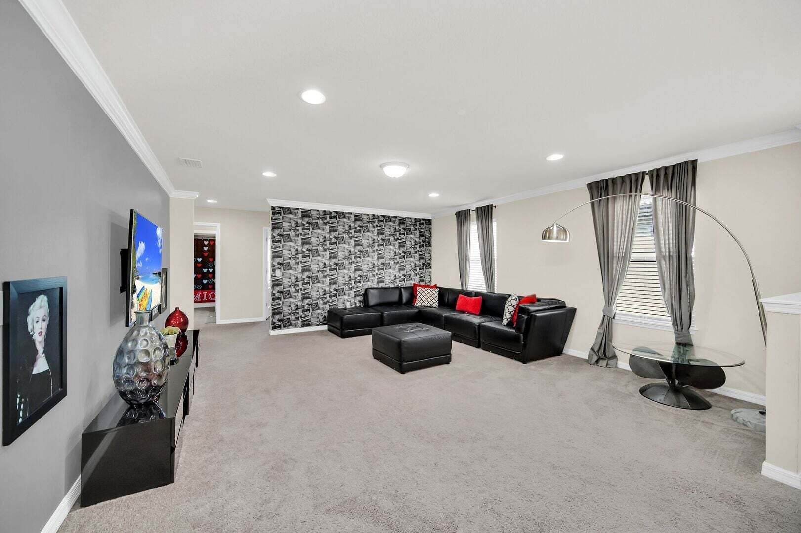 Un salon moderne avec un canapé d’angle, un téléviseur à écran plat, un mur décoratif et une lampe sur pied.