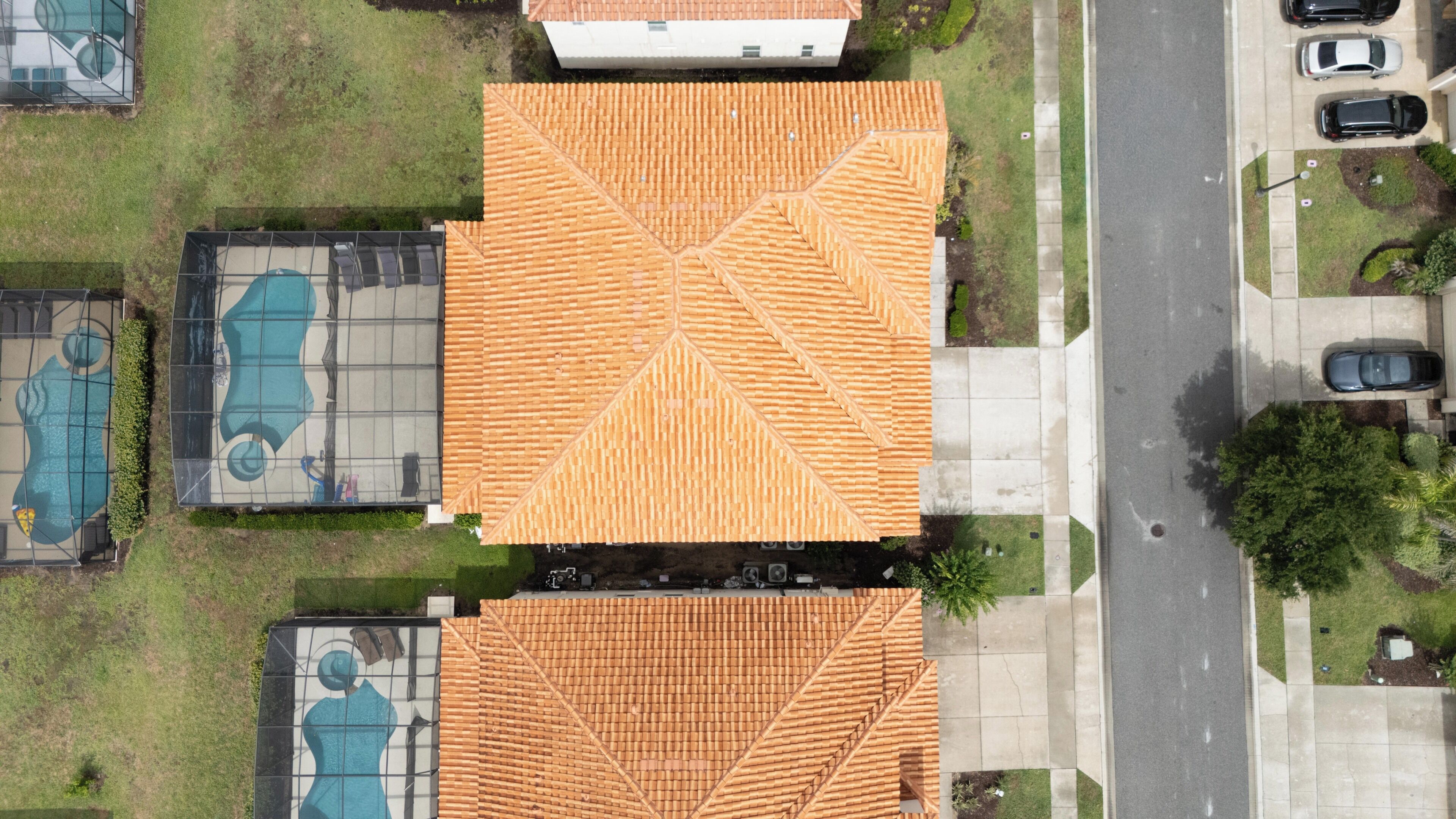 An aerial view of a building with a tiled roof, a swimming pool, and a mural.