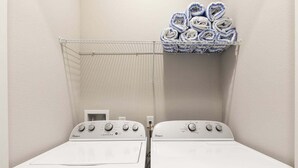 Ein Waschbereich mit zwei weißen Whirlpool Waschmaschinen und einem Metalltrocknergestell mit gefalteten Handtüchern.