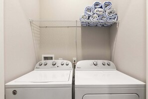 Une buanderie équipée de deux lave-linge Whirlpool blancs et d’un étendoir métallique sur lequel sont pliées des serviettes.