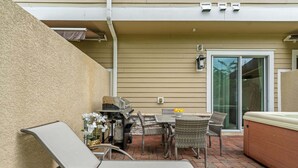 Eine Terrasse im Freien mit Grill, Stühlen und einem Tisch.