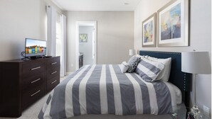 Ein Schlafzimmer mit einem Bett, einem Schminktisch, einem Fernseher und Bildern an der Wand.
