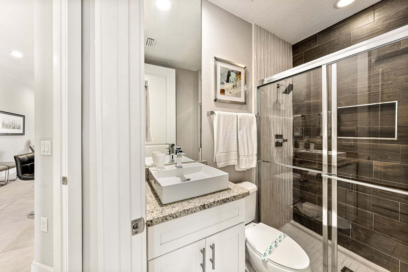 Un baño moderno con cabina de ducha de vidrio, un lavamanos blanco y un inodoro.