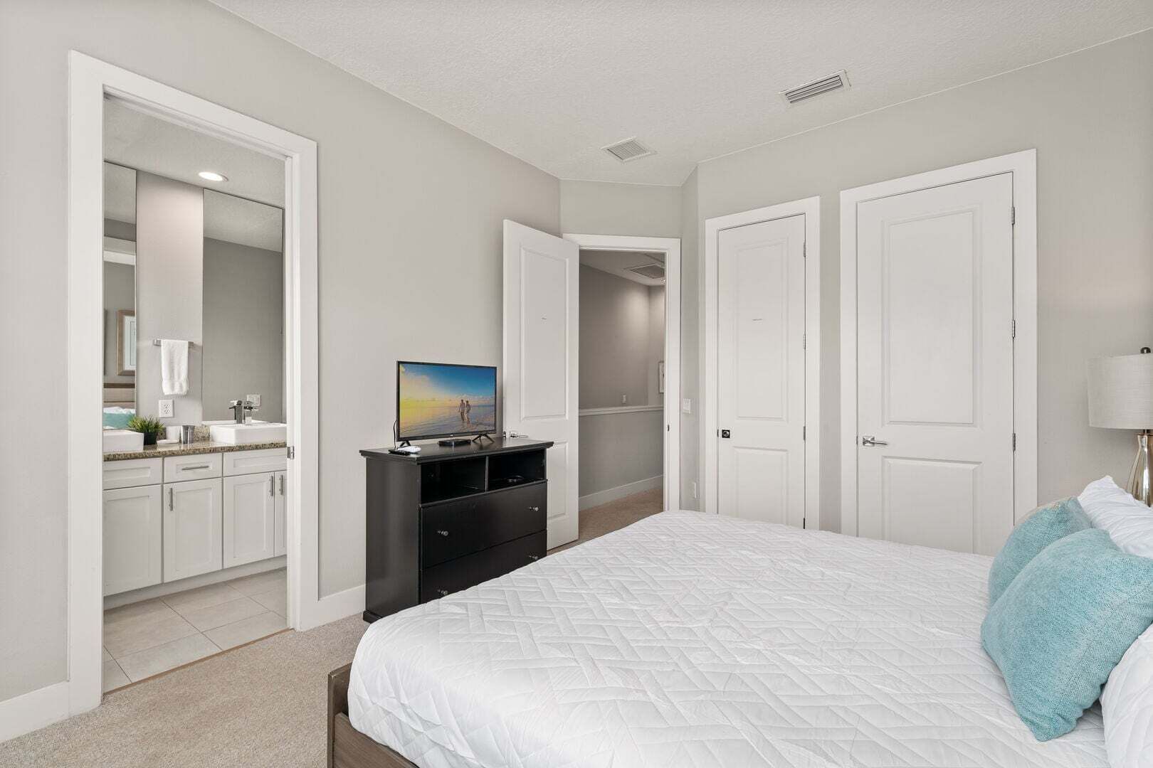 A bedroom with a bed, a dresser, a TV, and a closet.