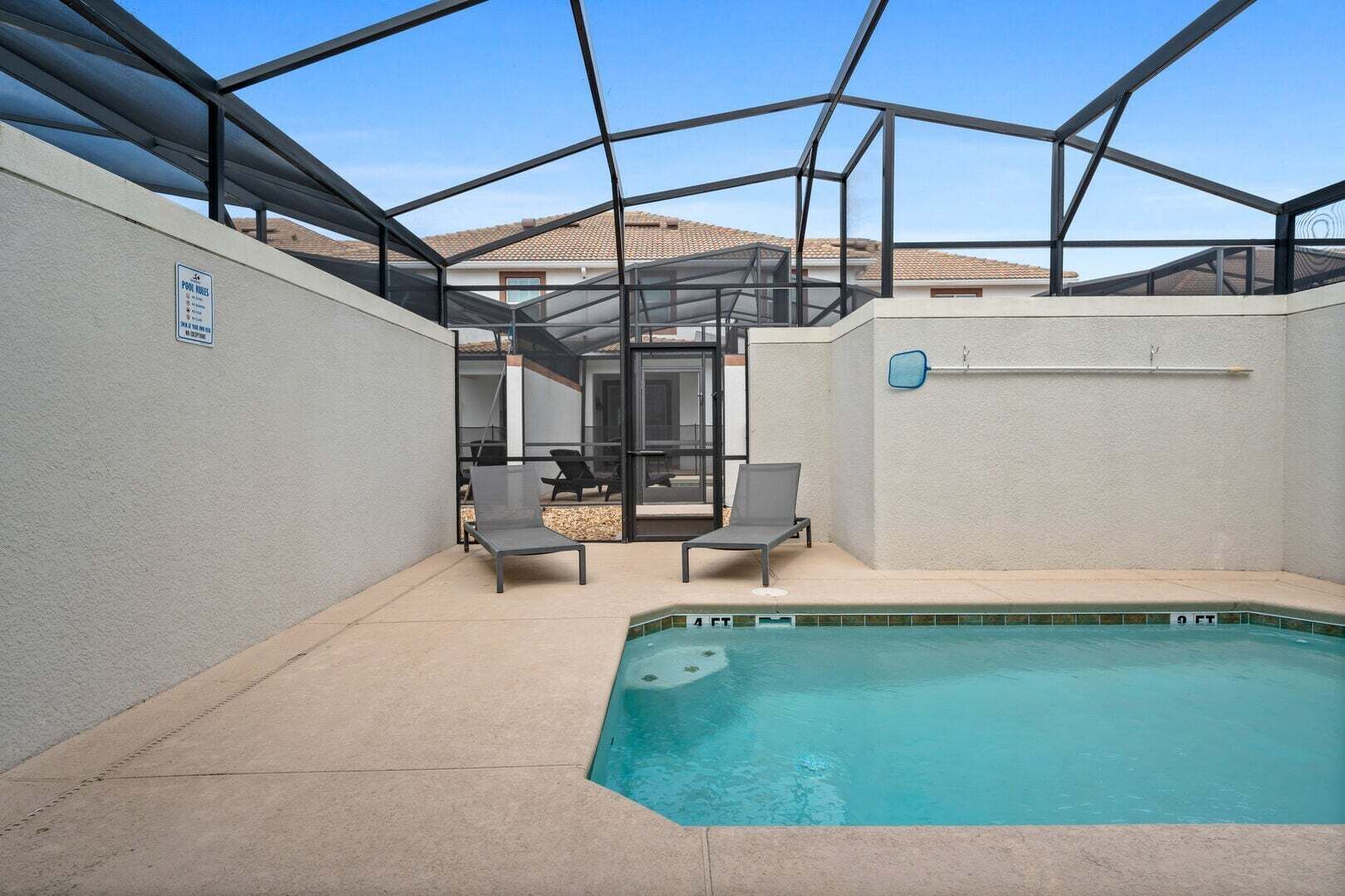 Une piscine avec des chaises longues, un patio couvert et une vue dégagée sur les bâtiments environnants.