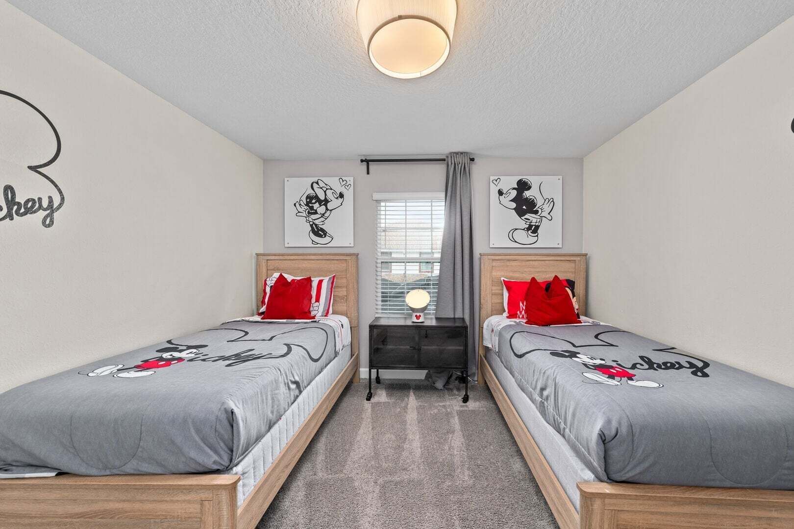 A bedroom with two beds, a nightstand, a mirror, and artwork on the walls.