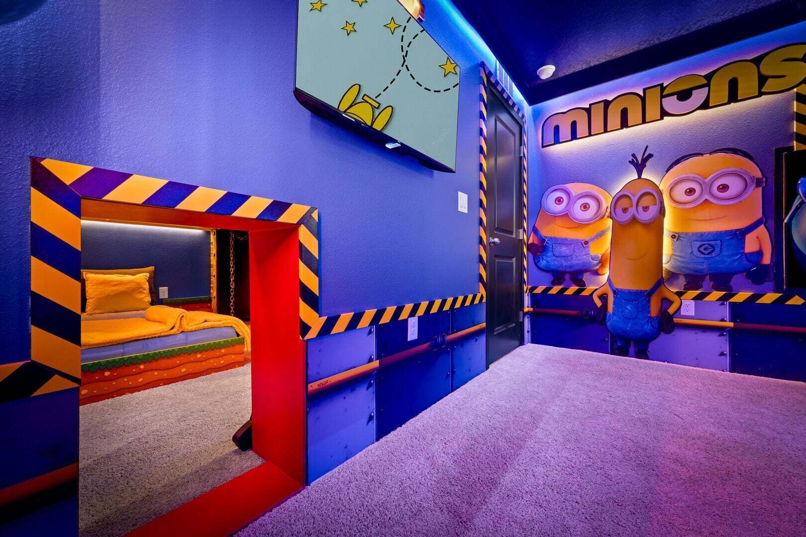 Une chambre d’enfant avec un lit, un espace de jeux et des décorations sur le thème des Minions.