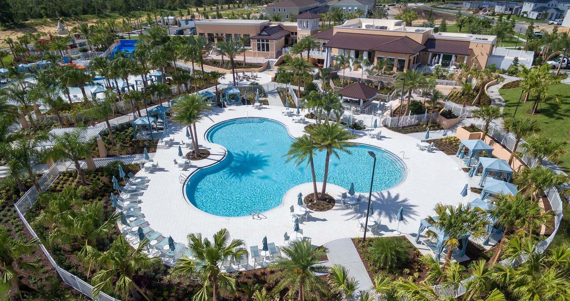 A resort with a central swimming pool, surrounded by palm trees and lounge chairs.