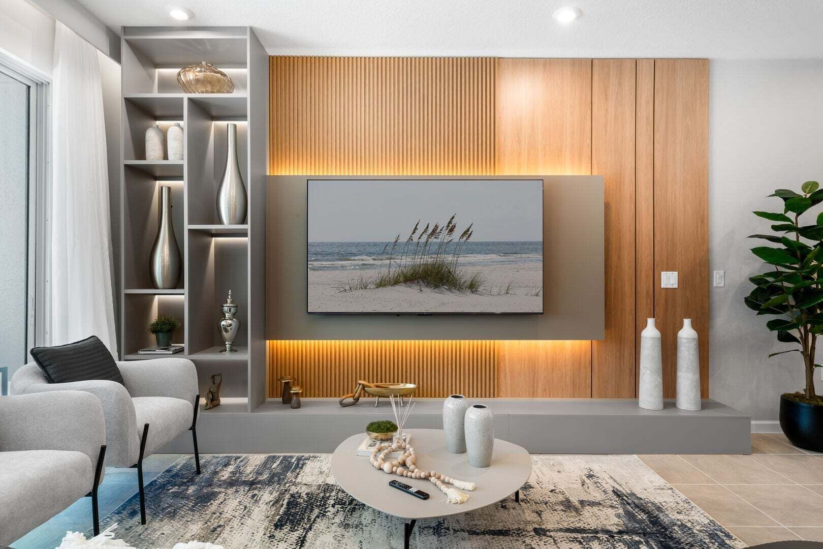 Ein modernes Wohnzimmer mit großem Flachbildfernseher, einer Couch, einem Couchtisch und Dekoration.