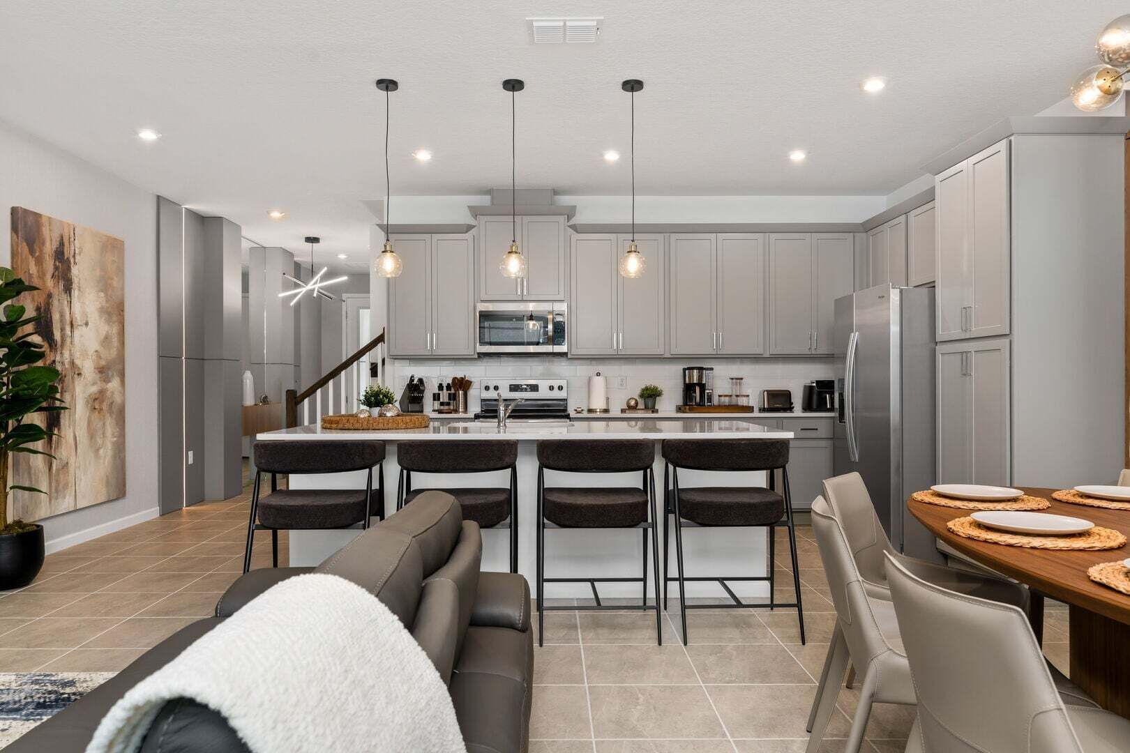 Una cocina moderna con una isla central, electrodomésticos de acero inoxidable e iluminación colgante.