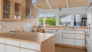 Eine moderne Küche mit Holzschnitzereien, einer zentralen Kochinsel und Blick nach draußen.