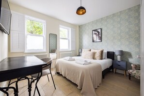 Ein Schlafzimmer mit einem Bett, Nachttischen, einem Schreibtisch und einem Sessel.