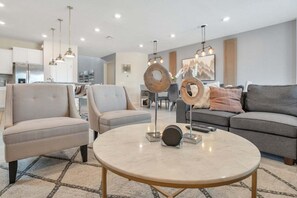Ein modernes Wohnzimmer mit einem runden Tisch, zwei Sesseln, einem Sofa und dekorativen Holzelementen.