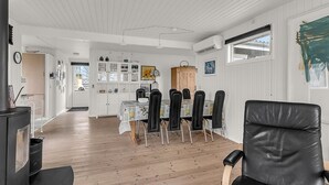Een moderne keuken met witte kasten, een eettafel met stoelen en een zwarte leren fauteuil op de voorgrond.