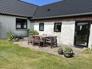 A house with a tiled roof, a brick section, a patio with a table and chairs, and potted plants. - "Jorek" - 700m from the sea by Interhome (Lemvig)