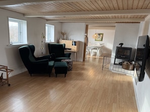 A living room with a sofa, a dining table, a TV, and a fireplace. - "Jorek" - 700m from the sea by Interhome (Lemvig)