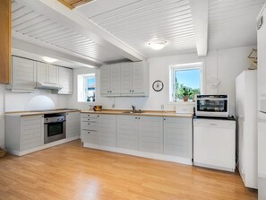 Una cocina moderna con armarios blancos, encimeras de madera y electrodomésticos integrados.