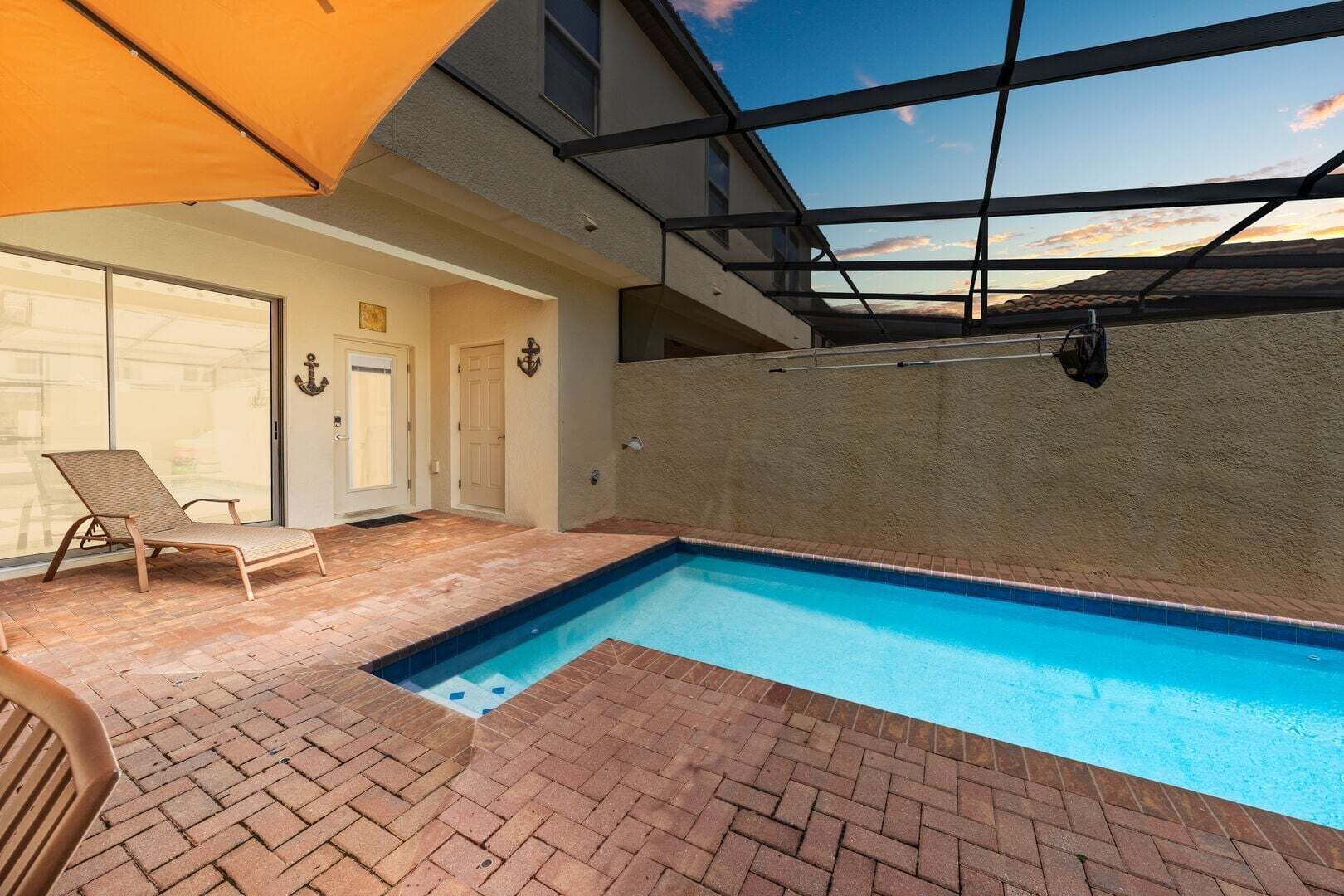An indoor swimming pool with a glass ceiling, a lounge chair, and a door with an anchor decoration.