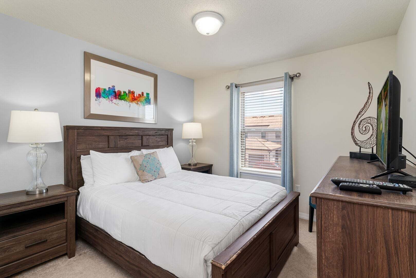 Een hotelkamer met een bed, twee nachtkastjes, een televisie en een raam met zonwering.