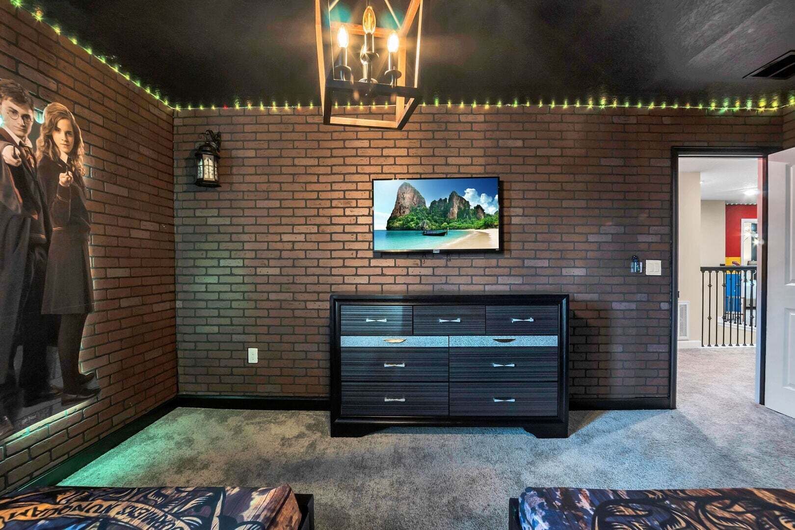 Een kamer met een bakstenen muur, een zwarte entertainmentkast, een lijst met een afbeelding en een kroonluchter.
