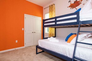 Ein Mehrbettzimmer mit orangefarbener Wand, einer weißen Tür und einem Fenster mit gelben Vorhängen.