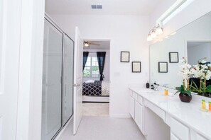 A modern bathroom with a large mirror, white cabinets, and a shower area. - Gorgeous Family Home! Sleeps 28 (Kissimmee)
