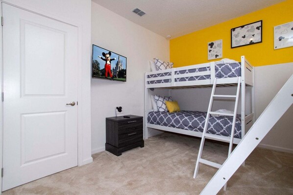 A bunk bed room with a door, a small cabinet, and a picture of Mickey Mouse on the wall. - Gorgeous Family Home! Sleeps 28 (Kissimmee)