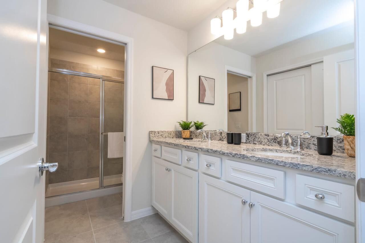 A bathroom with a shower, a sink with a mirror, and cabinets.