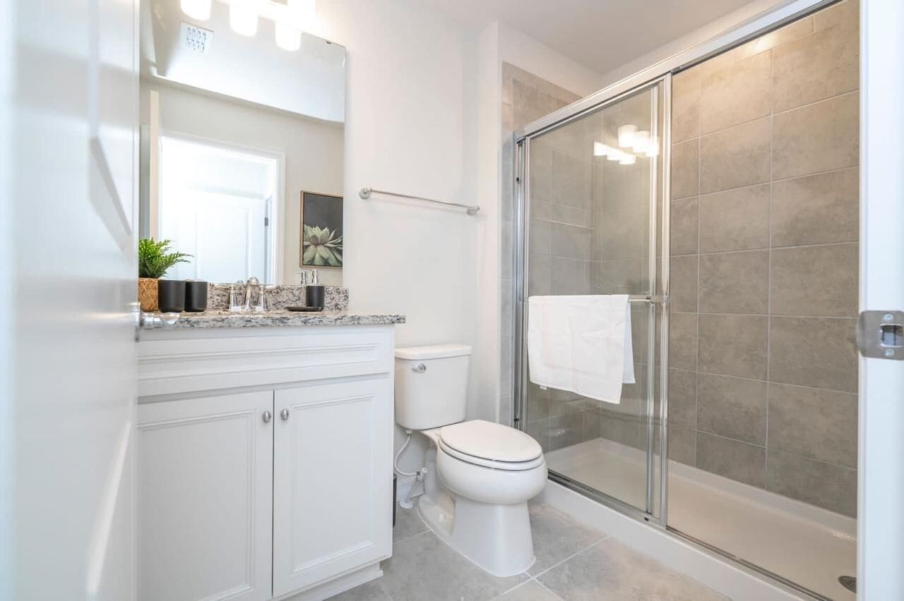A modern bathroom with a glass shower enclosure, a white toilet, and a marble countertop.