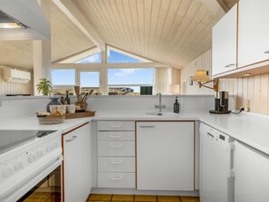 Eine moderne Küche mit weißen Schränken, einem Backofen, einer Spüle und einer Kaffeemaschine.