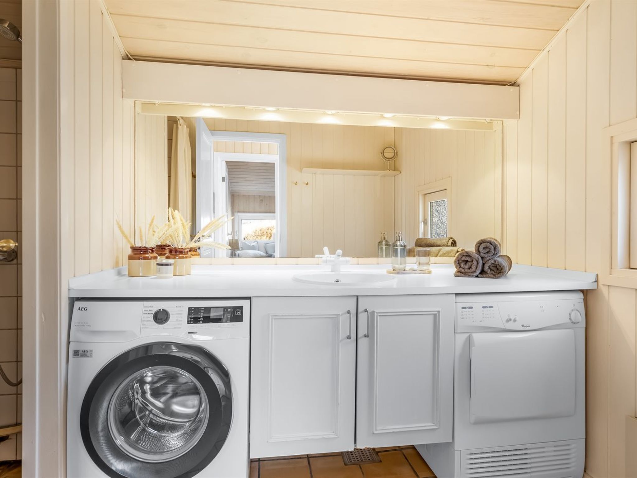 Une buanderie équipée d’un lave-linge, d’un sèche-linge, d’un évier et d’un miroir.