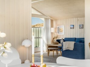 Ein Zimmer mit einem blauen Sofa, einem Tisch mit einer Lampe und Blick ins Freie.