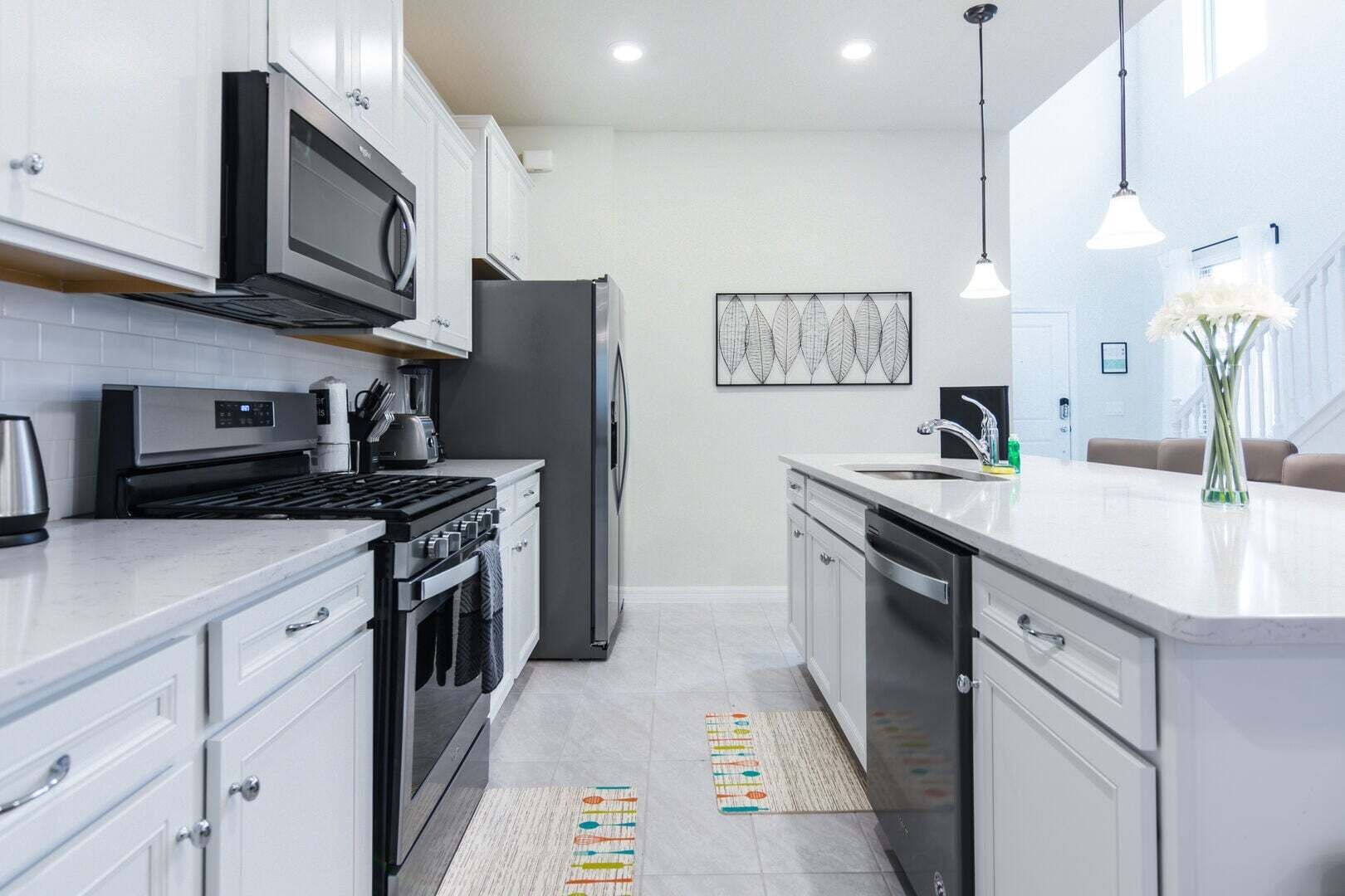 A modern kitchen with stainless steel appliances, white cabinetry, and a central island with a sink.