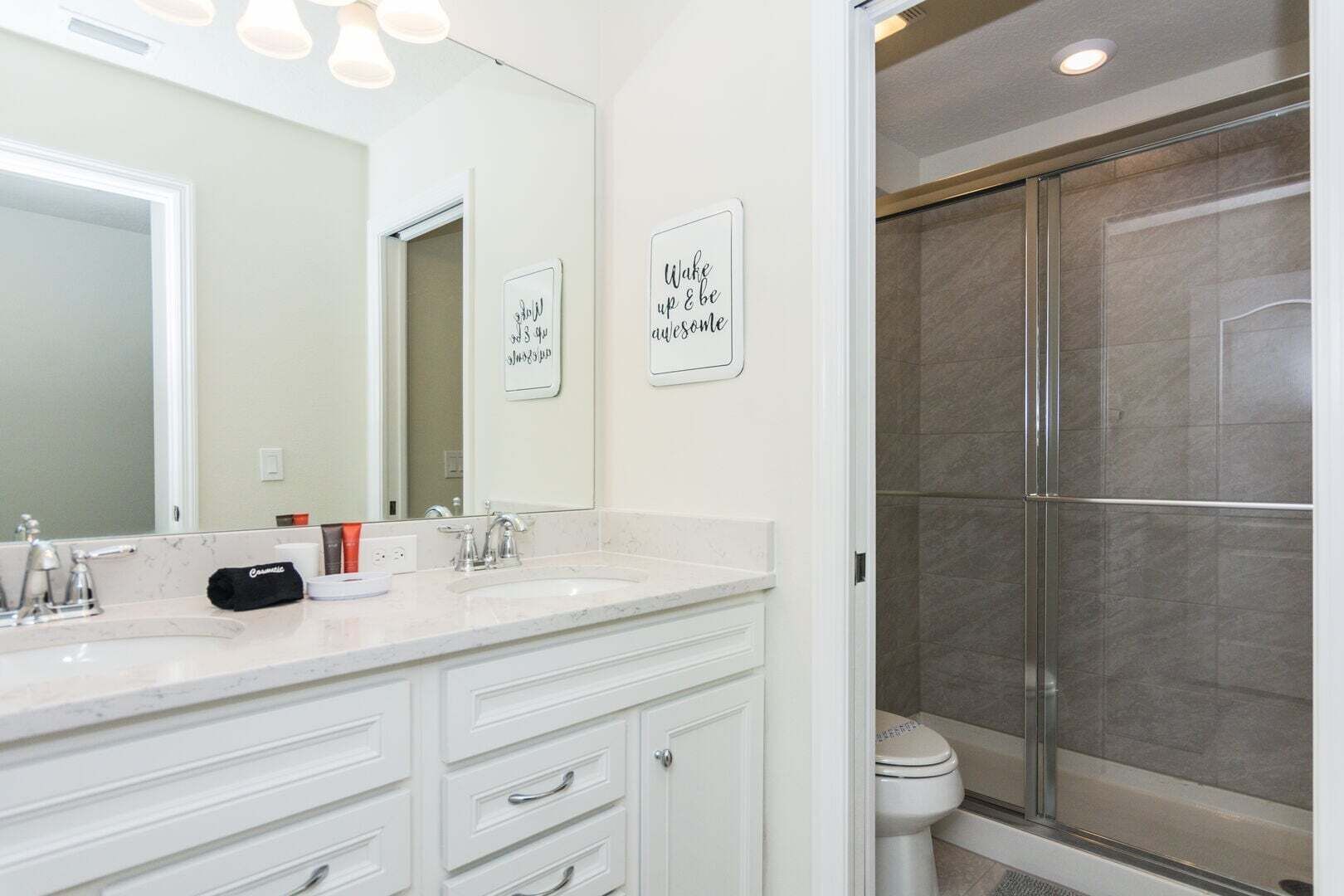 Un bagno con due lavandini, uno specchio grande e una doccia con porta in vetro.