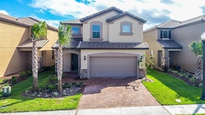 A two-story residential building with a garage, a front lawn, and a clear sky. - Fantastic Home at Solterra Sol102 (Davenport)