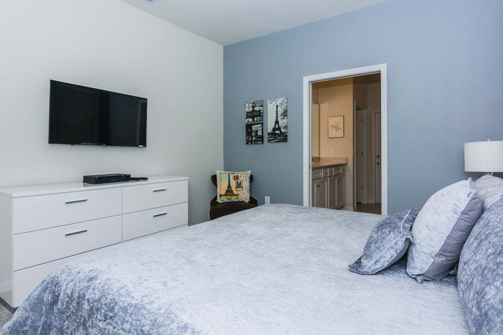 Een slaapkamer met een bed, een televisie, een dressoir en een deur naar de badkamer.