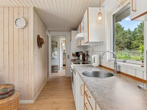 Eine moderne Küche mit Holzwänden, einem großen Fenster und Blick ins Grüne.