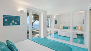Un dormitorio con cama, un baño con espejo y vistas al mar.