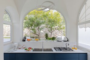 A modern kitchen with a large window, a gas stove, and a sink. - Villa Vento Blu, Exclusive Luxury in Capri (Anacapri)